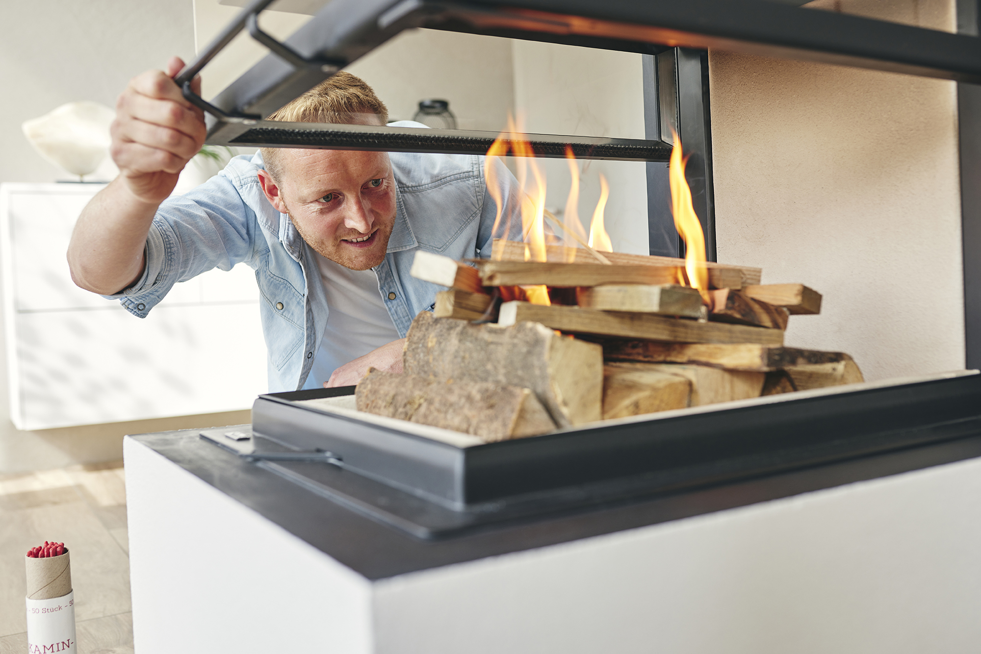Mann feuert einen Heizkamin an