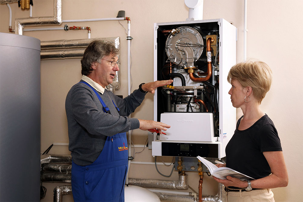 Handwerker vor Brennwerttechnik mit Hausbesitzerin