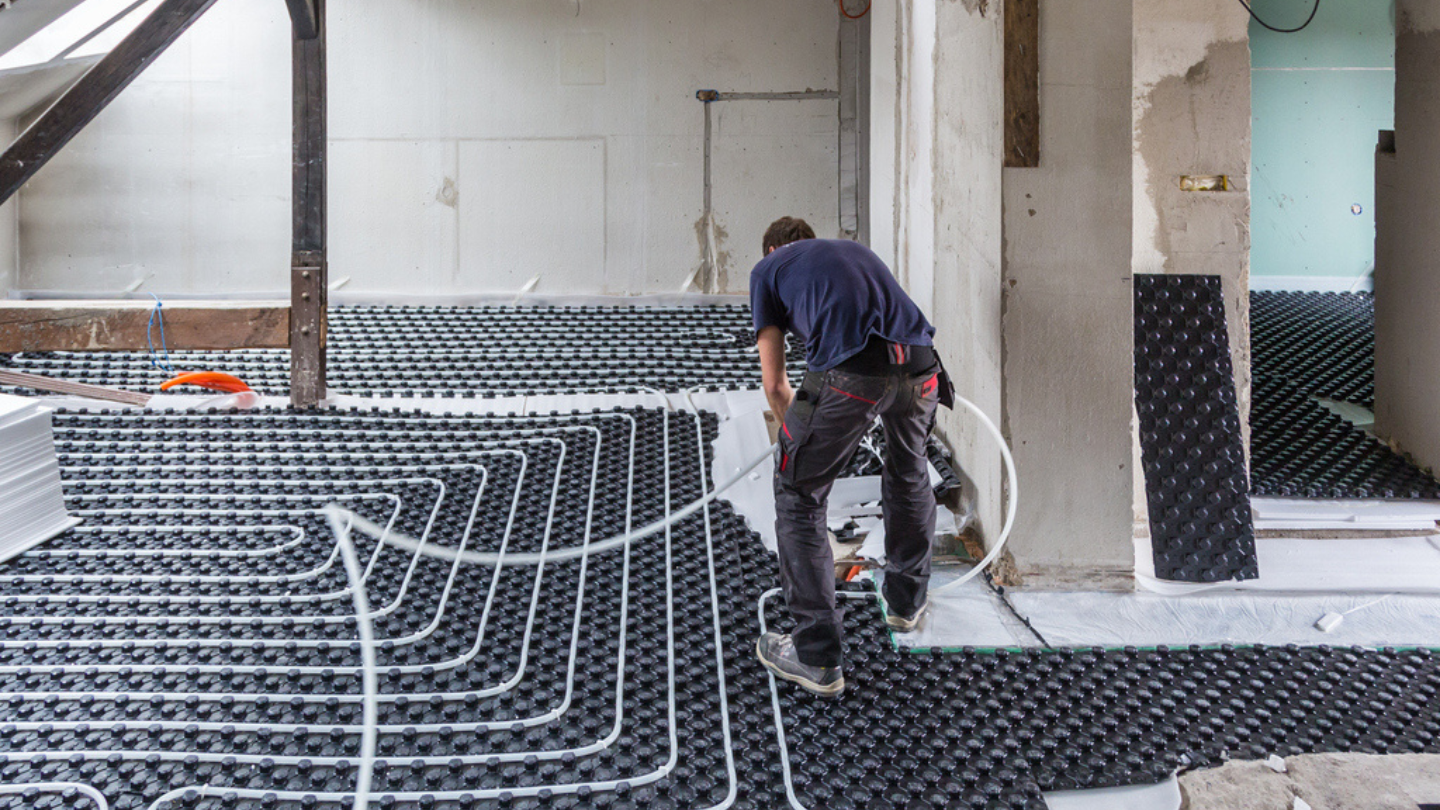 Handwerker verlegt eine Fußbodenheizung