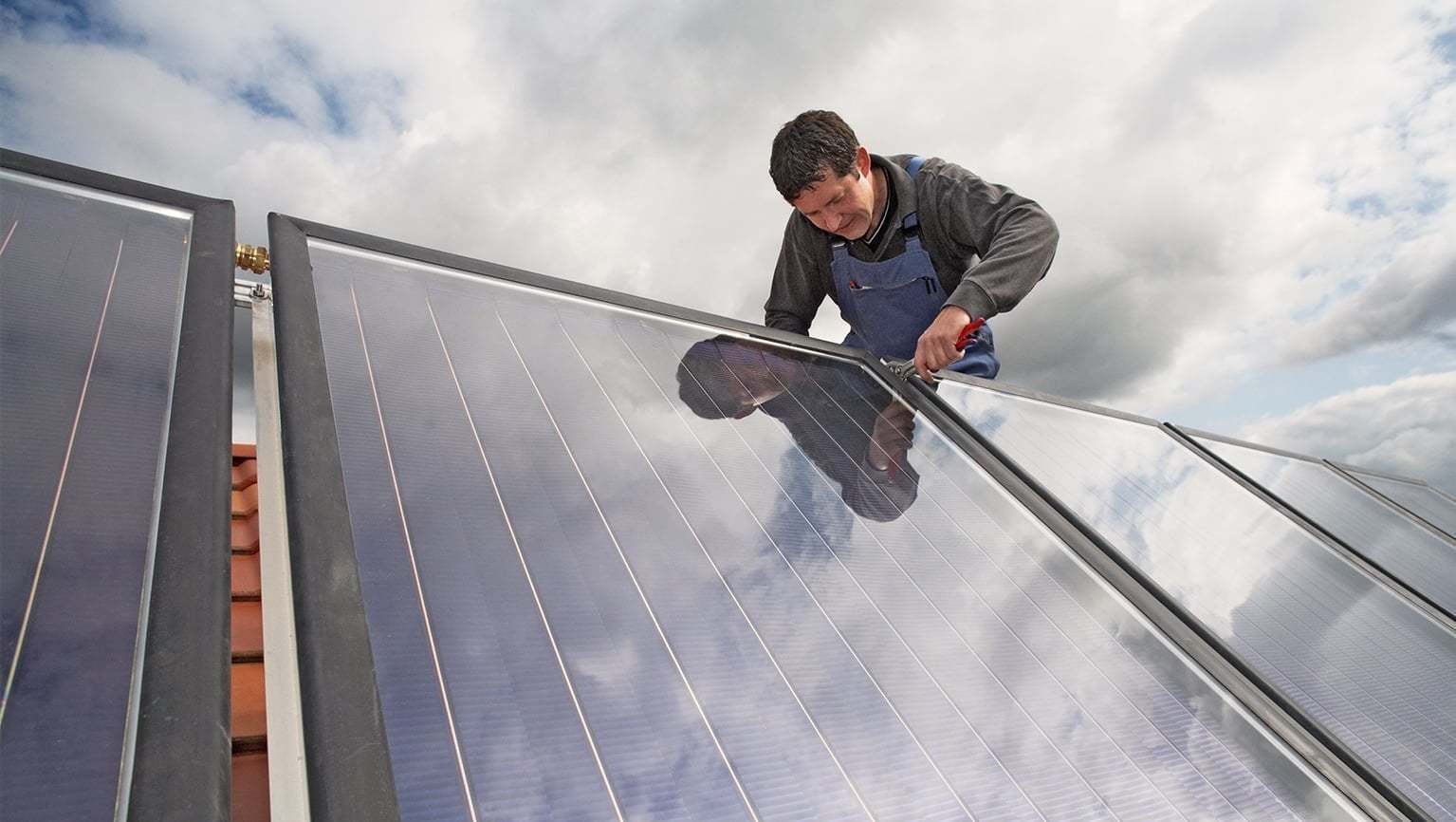 Ein Fachmann repariert ein Solarmodul auf einem Dach. 